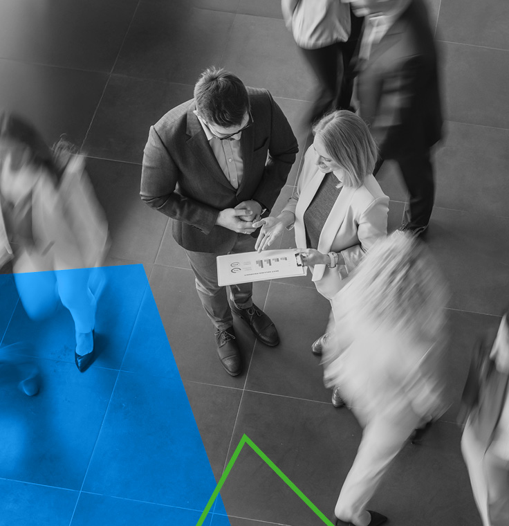 Des collègues conversant et marchant rapidement dans un hall de bureau moderne à aire ouverte.