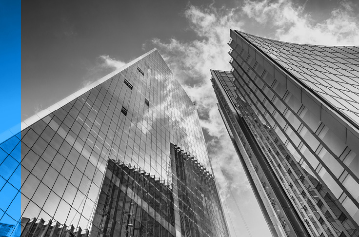 Deux tours de bureaux réfléchissantes, dressées sous de légers nuages.