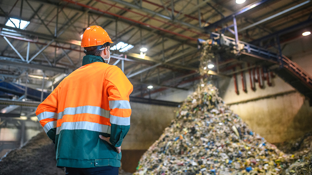 Un homme regarde des déchets déversés dans une usine.